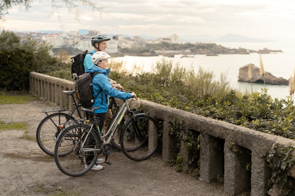 un couple se promène à vélo à biarritz et regarde la mer
