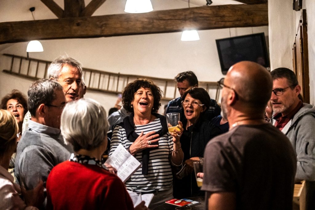 restaurant cidrerie du fronton à Arbonne au Pays basque, des gens chantent devant un txox et boivent un verre de cidre