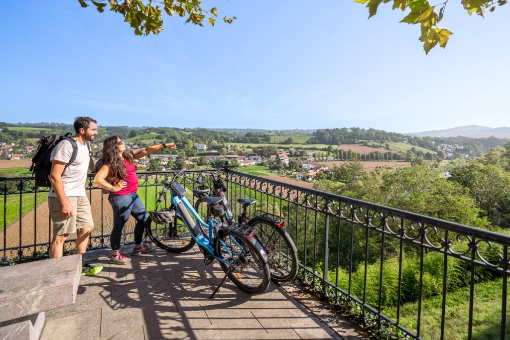 un couple se promène à vélo et admire la vue depuis cambo les bains sur la campagne basque